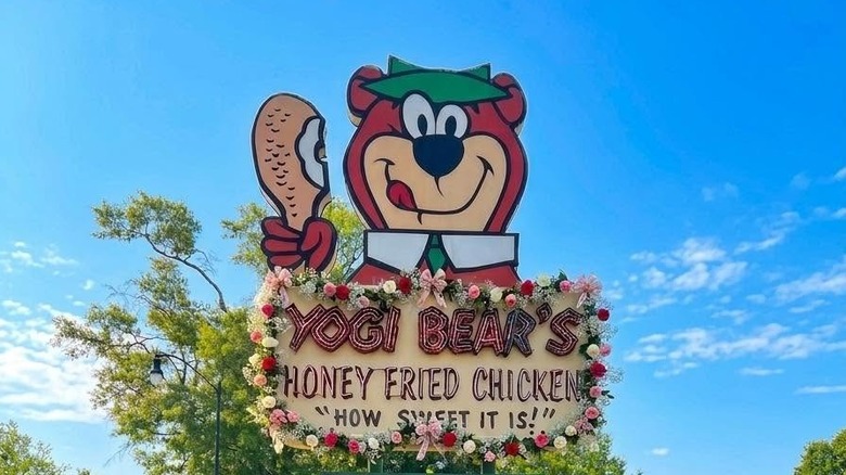 A sign of yogi bear's honey fried chicken on the side of the road with the phrase "How Sweet It Is" written under it
