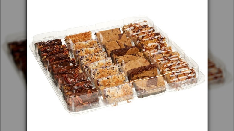 Container with variety dessert bars including brownies and brookies on a white background