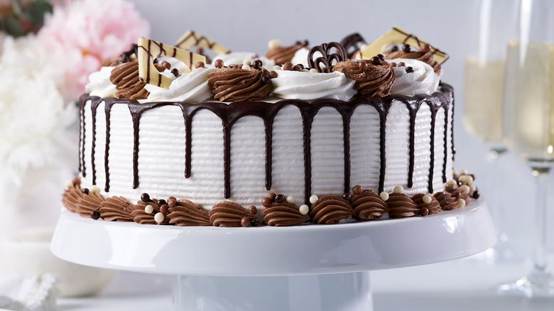 A white cake with chocolate drizzle, decorated with mousse and chocolate candy.