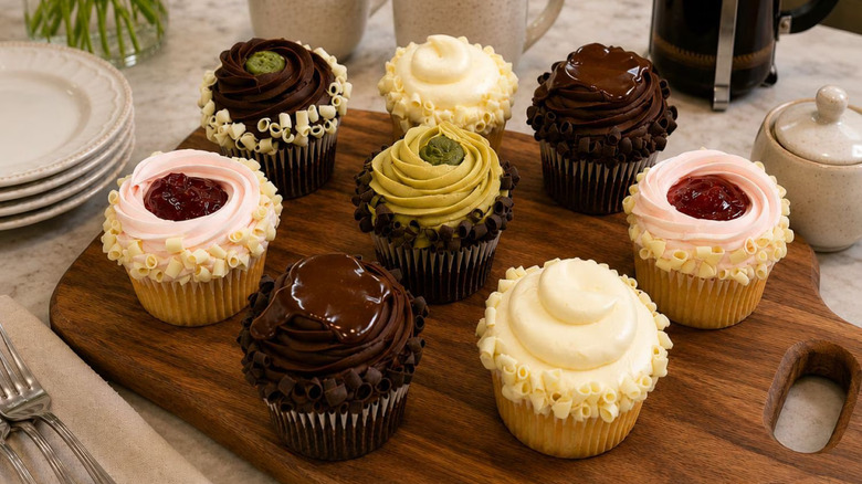 A variety of chocolate and vanilla cupcakes displayed on a cutting board.