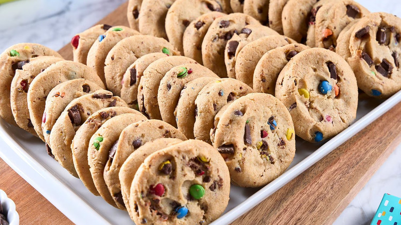 Chocolate chip cookies filled with colorful candy, arranged on a tray.