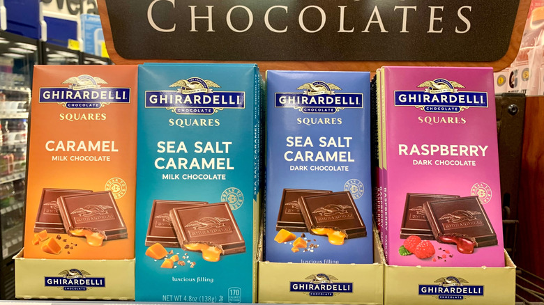 Assorted packages of Ghirardelli Chocolate Squares on display in a grocery store