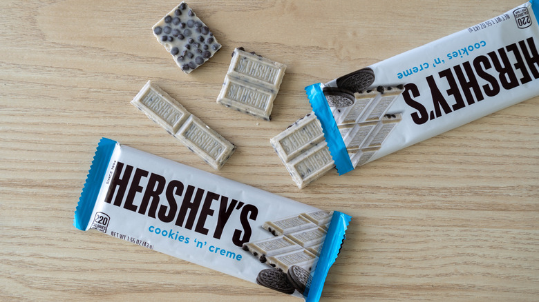 Overhead shot of Hershey's Cookies 'n' Creme bar, both wrapped and unwrapped, showing both sides of the white chocolate candy bar with cookie pieces