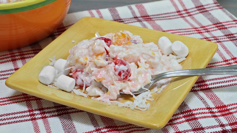 A spoon sticking out of a yellow plate of ambrosia salad