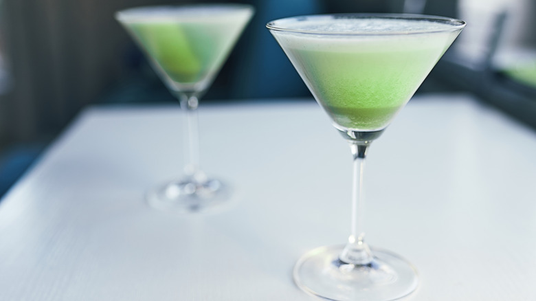 Two martini glasses with frothy green cocktails
