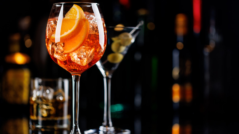 Orange cocktail with martini and whiskey on the rocks in the background