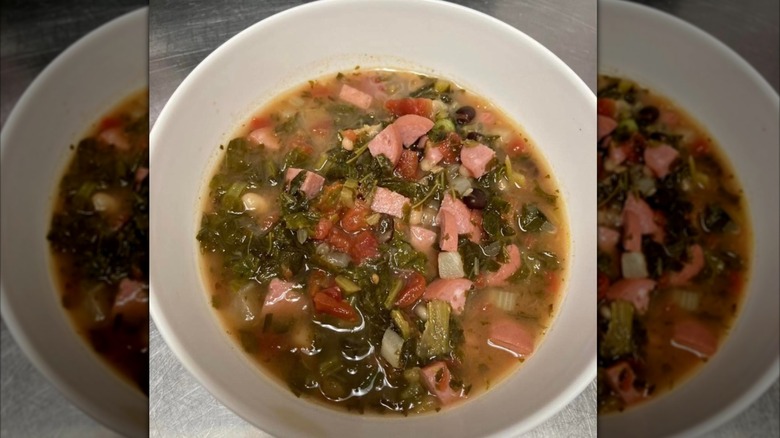 White bowl of swamp soup on grey table, mirrored image.