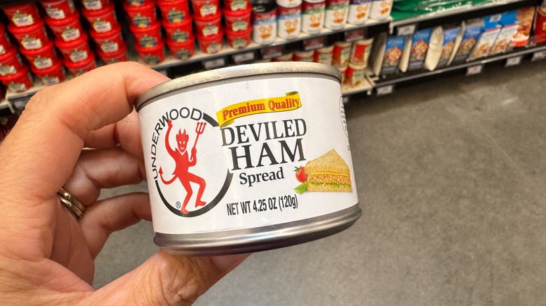 Hand holds a can of Deviled Ham spread at the grocery store