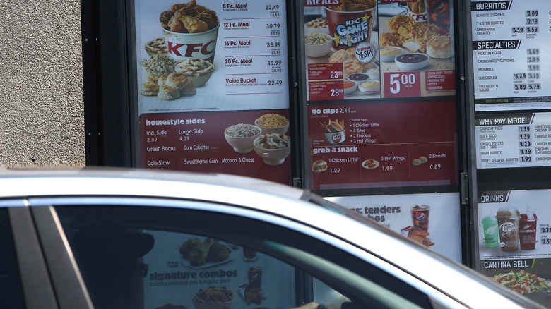 White car at a KFC drive-thru sign.