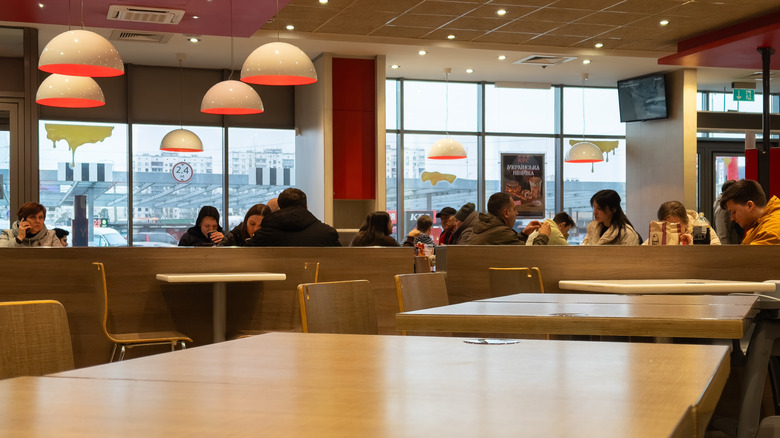 Customers in a half-empty KFC, with empty tables in foreground.