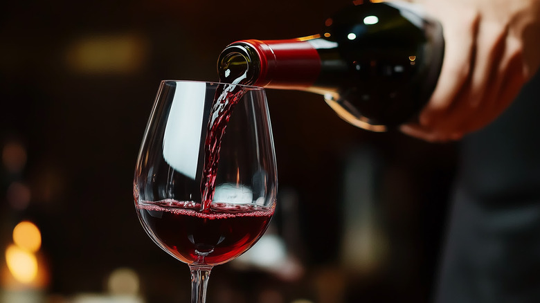 Server pouring red wine in glass at restaurant