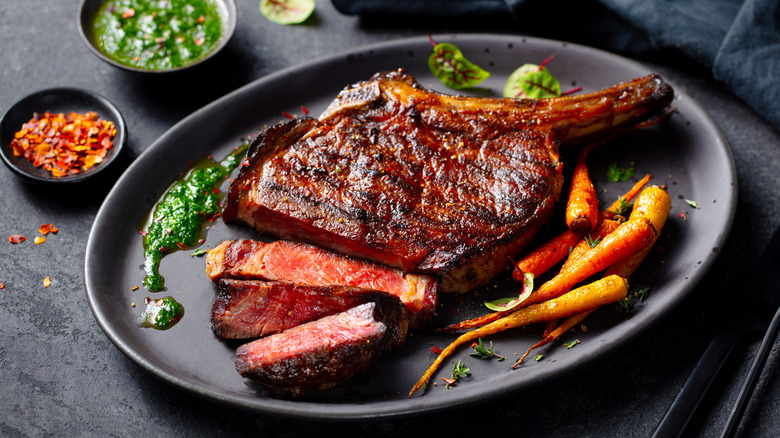 Sliced steak on black plate with carrots and garnishes