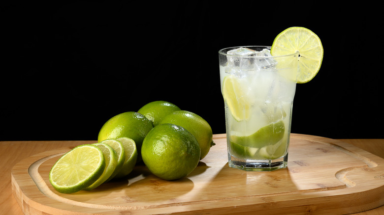 Caipirinha with lime next to several other limes