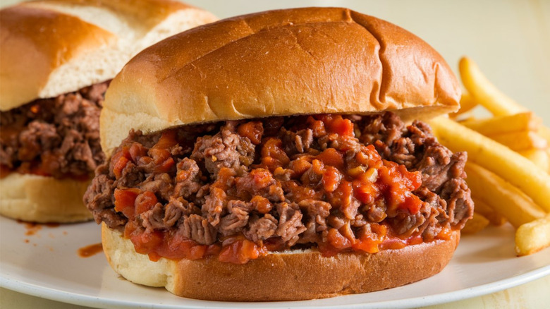 sloppy joe burgers with fries on a white plate