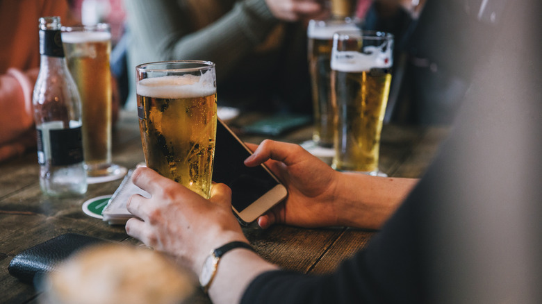 Beers on table with smartphone in hand
