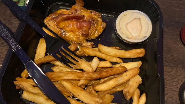A to-go order of Alice Springs chicken with a tiny chicken portion, sauce, and limp fries