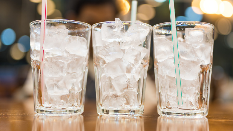 Three glasses with straws empty of everything but ice