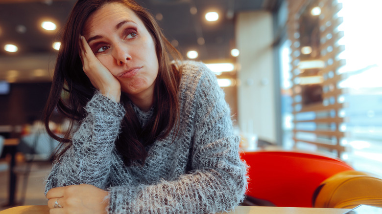 Woman looking bored while waiting at a restaurant table