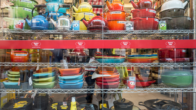 Large retail display of colorful Le Creuset products, including both enameled cast iron and stoneware