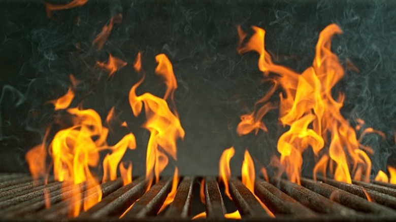 close-up image of a grill's cast-iron grates, with high flames licking above them