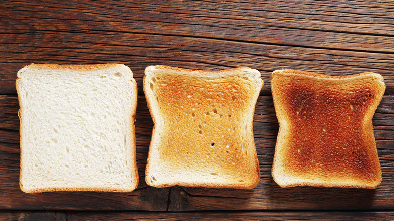 three slices of white, sliced sandwich bread, toasted to varying degrees