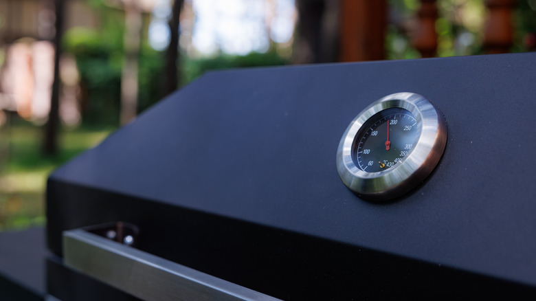 black grill's lid, with the built-in thermometer clearly visible in the foreground