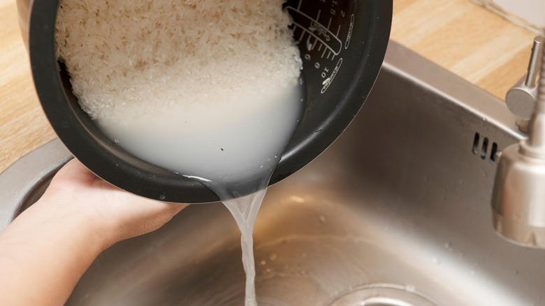 Hands rinsing white rice over sink