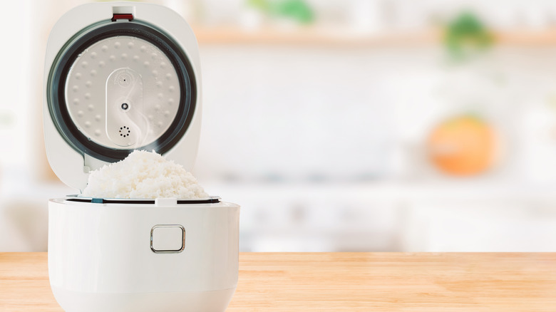 Overfilled white rice cooker on wooden table