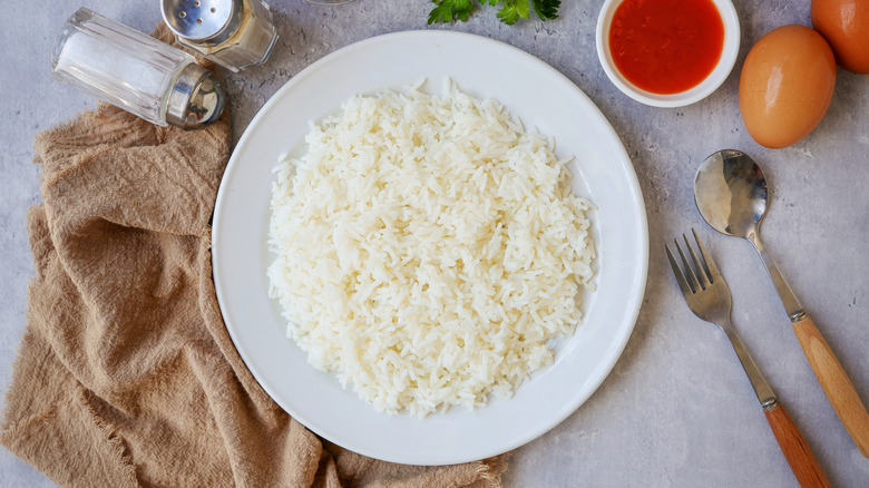 Cooked white rice on white plate with tan napkin