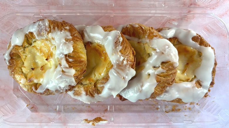 Overhead shot of open container of Costco cream cheese danishes on pink surface