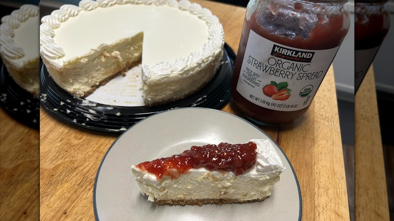 Slice of vanilla cheesecake on plate, topped with strawberry spread