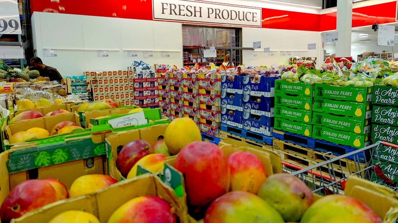 Boxes of mangoes and pears in foreground, Kirkland fresh produce fridge sign in background
