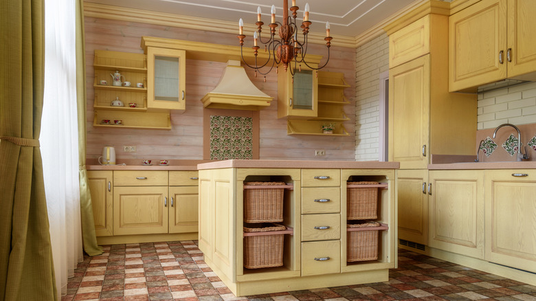 Old-fashioned wooden pastel yellow kitchen with a chandelier above the island