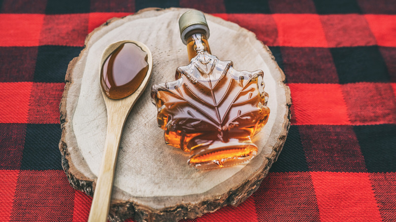 Maple syrup bottle with a spoon on a plaid tablecloth