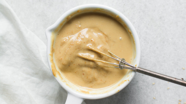 Peanut butter sauce being whisked in a ceramic cup