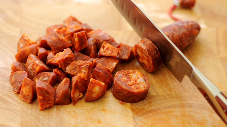 Chopping chorizo on wooden cutting board