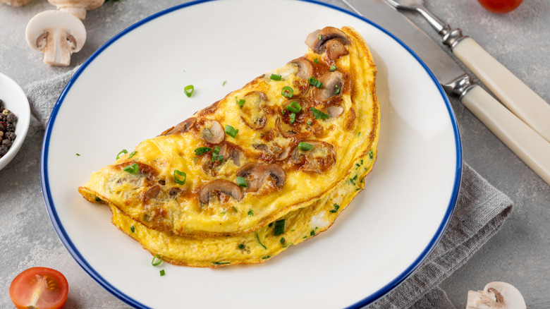 Omelet on plate will sliced mushrooms and chopped green onion