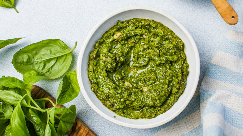Bowl of pesto next to fresh basil leaves