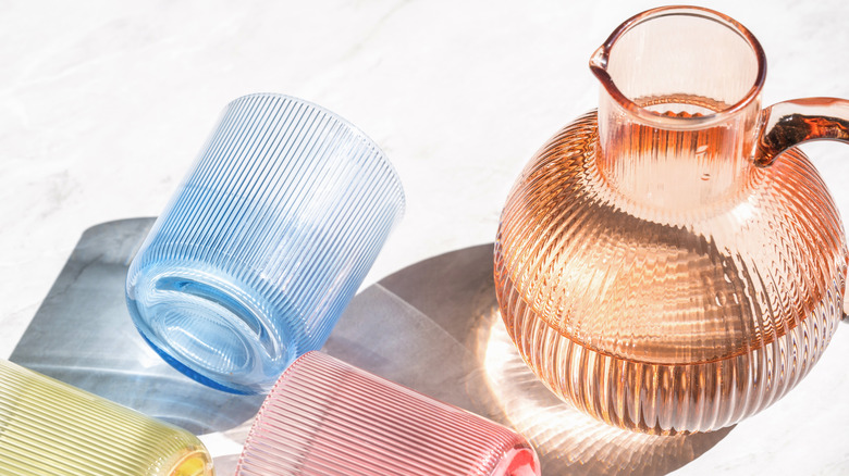 High view of a tinted glass pitcher alongside coloured glasses