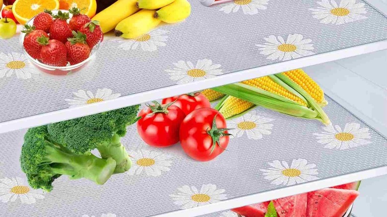 Interior of a refrigerator with fresh vegetables and fruits placed on a floral shelf liner