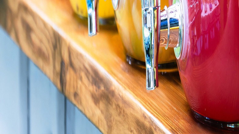 A series of decorated drink dispensers with lemonade and fruit juices placed on a wooden table