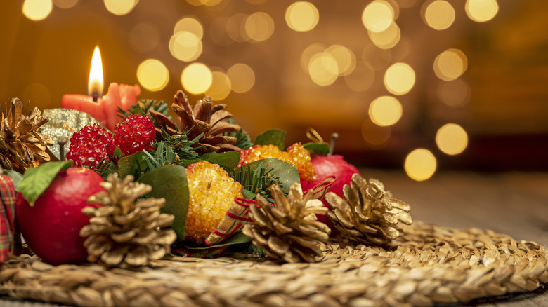 Festive fruit arrangement decorated with pine cones on a table mat