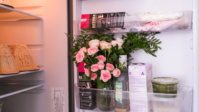 A vase of pink flowers placed on refrigerator door
