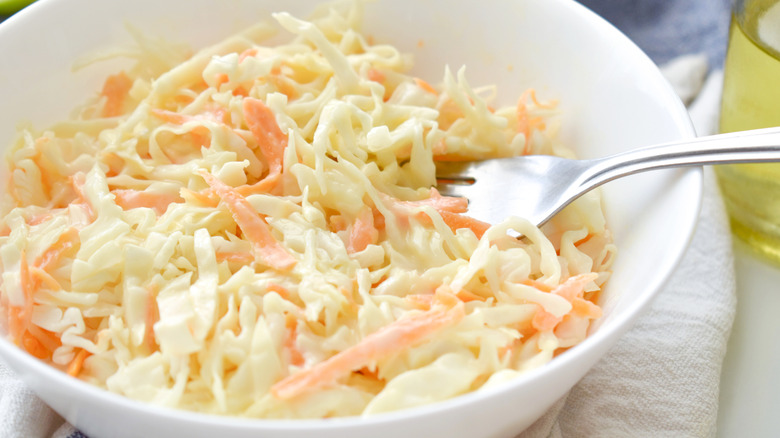 Fork digging into a bowl of creamy coleslaw