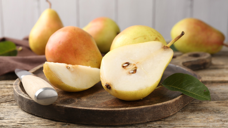 Sliced pears on a wooden platter with a knife