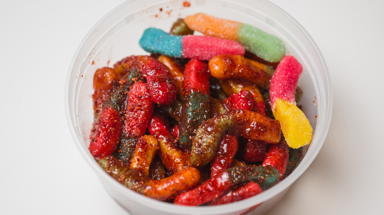 Sour gummy worms coated with chamoy