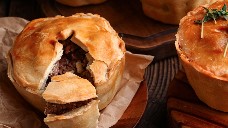 A small beef pot pie with a slice cut out of it with another pie next to it