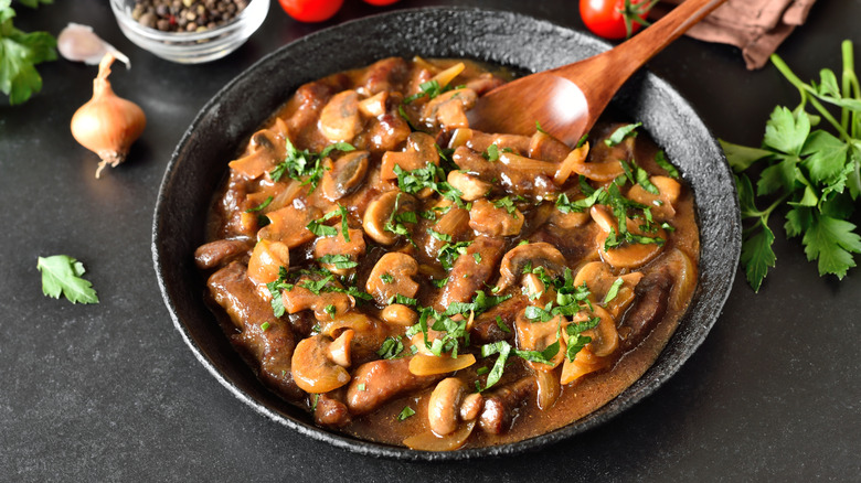 A pot of beef and mushroom stroganoff sauce topped with fresh parsley