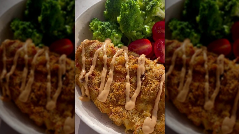 Almond-crusted chicken on plate with broccoli and tomatoes