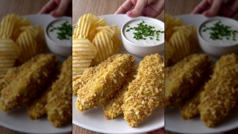 Potato chip-crused chicken tenders on plate with cream dip and potato chips